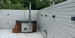 wood fire hot tub next to grey fence